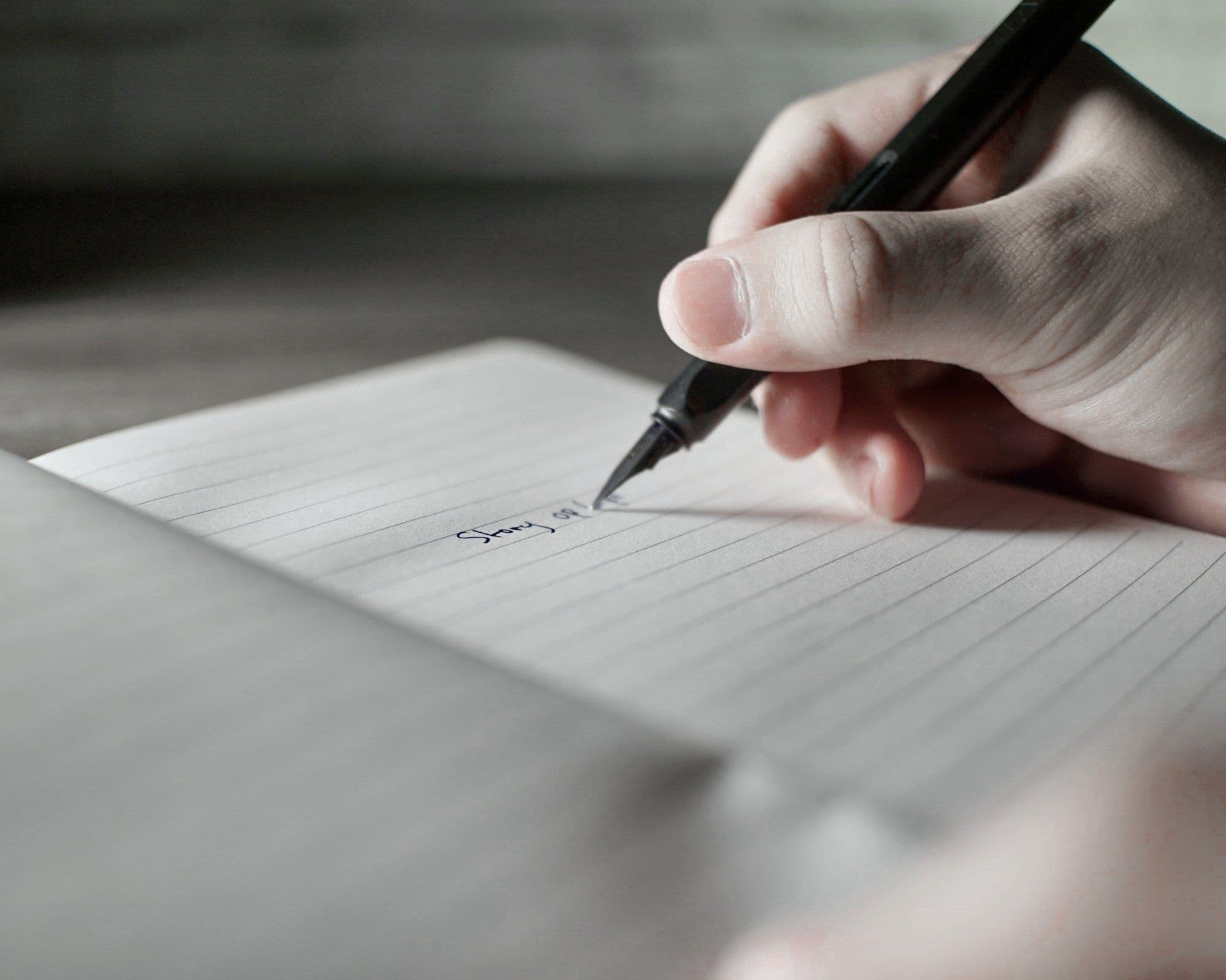 A hand writing the first words of a story with a fountain pen