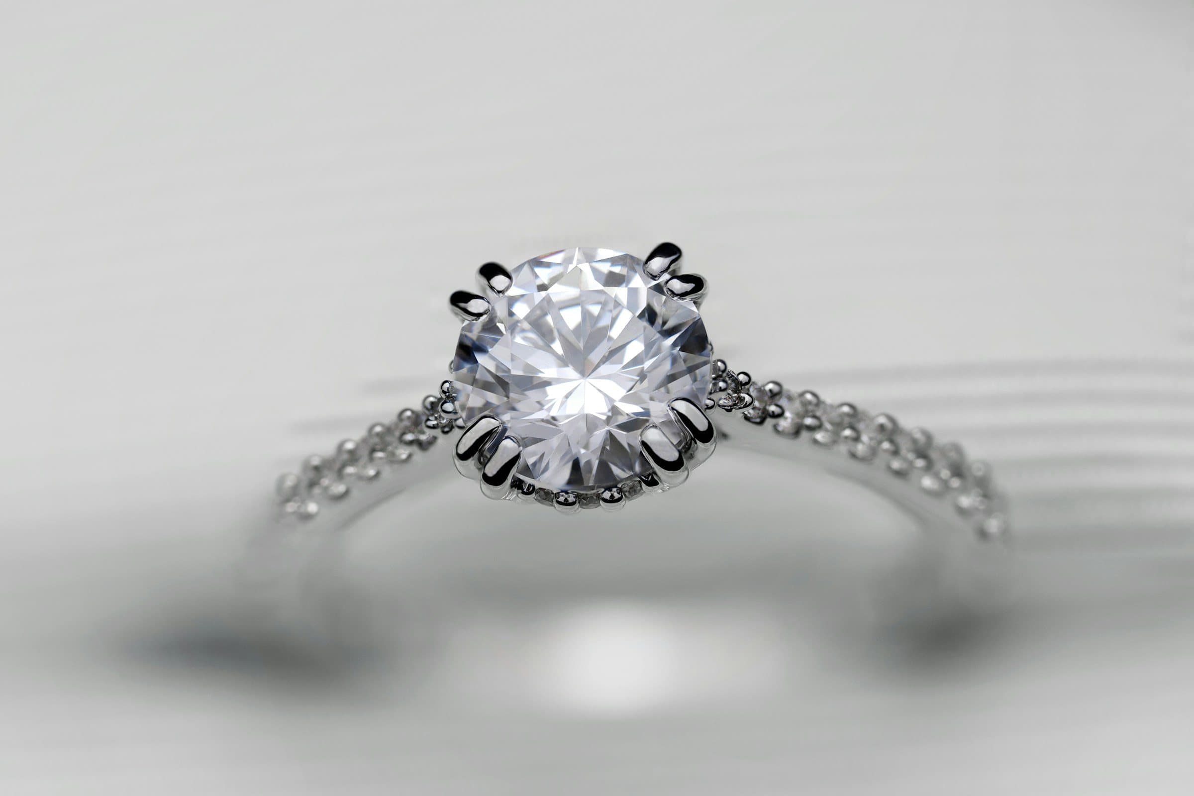 A platinum solitaire diamond ring resting on a soft white surface