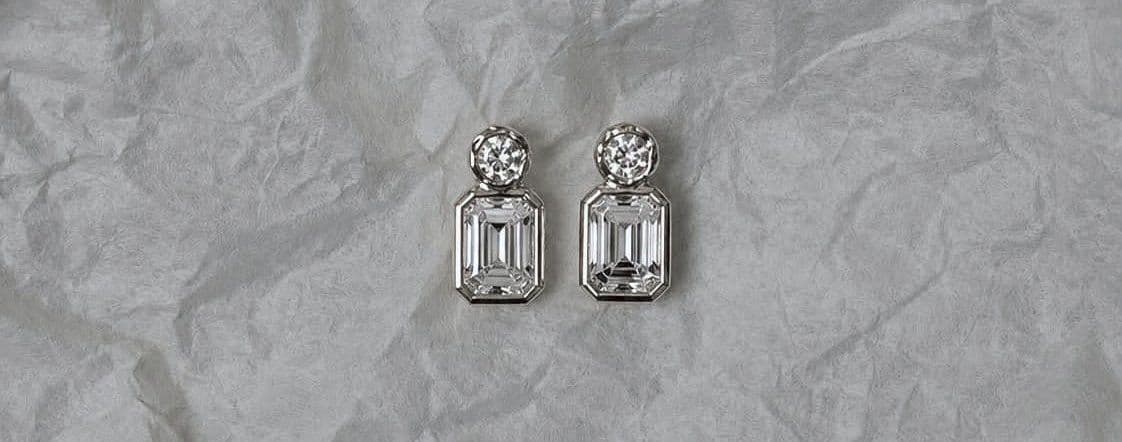 A pair of emerald-cut diamond earrings resting on soft paper