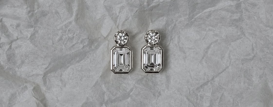 A pair of emerald-cut diamond earrings resting on soft paper