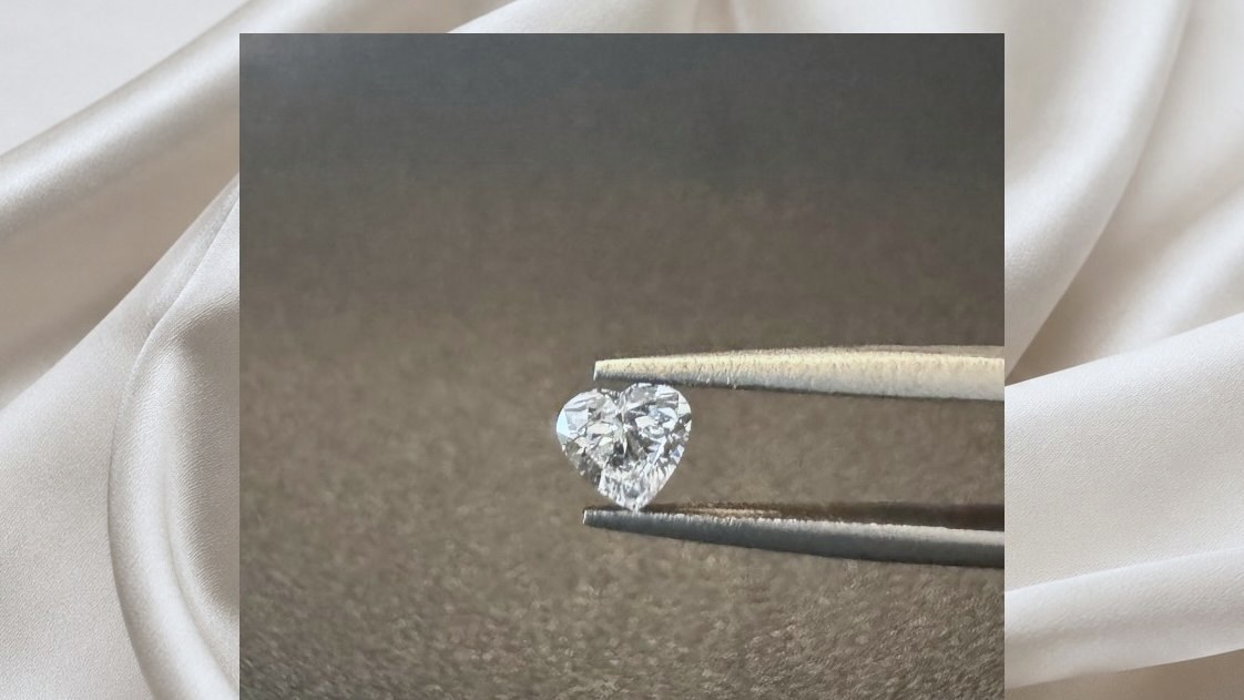 A finished diamond held up in tweezers