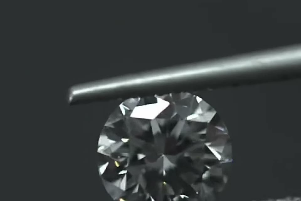 A finished brilliant-cut diamond held in tweezers