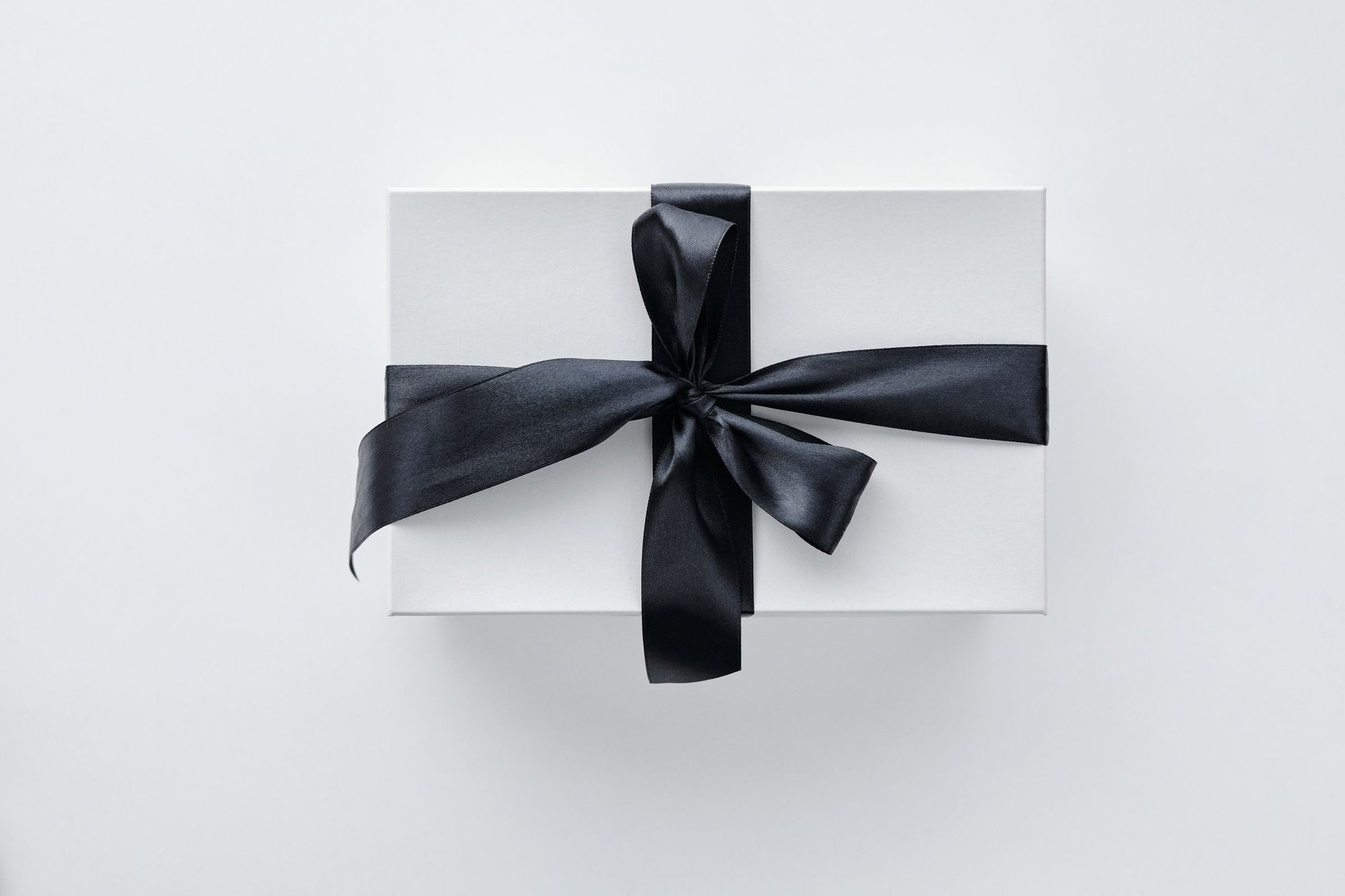 A pearl-white gift box tied with a black satin bow