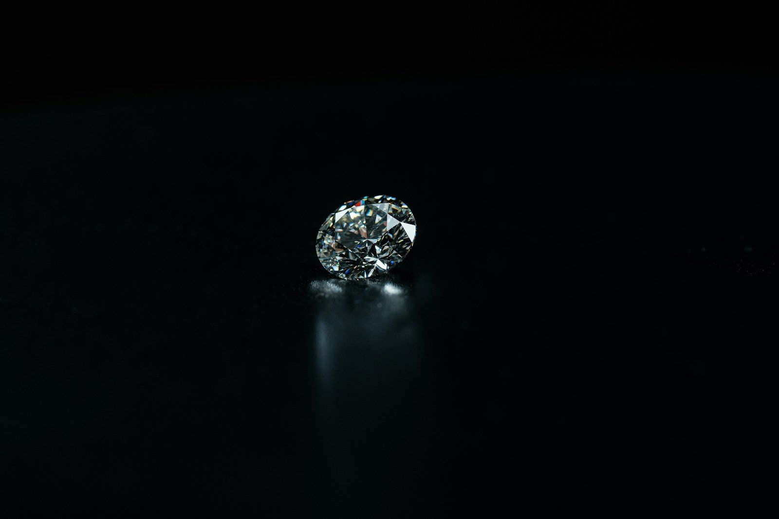 A single cut diamond resting in darkness, lit from one side